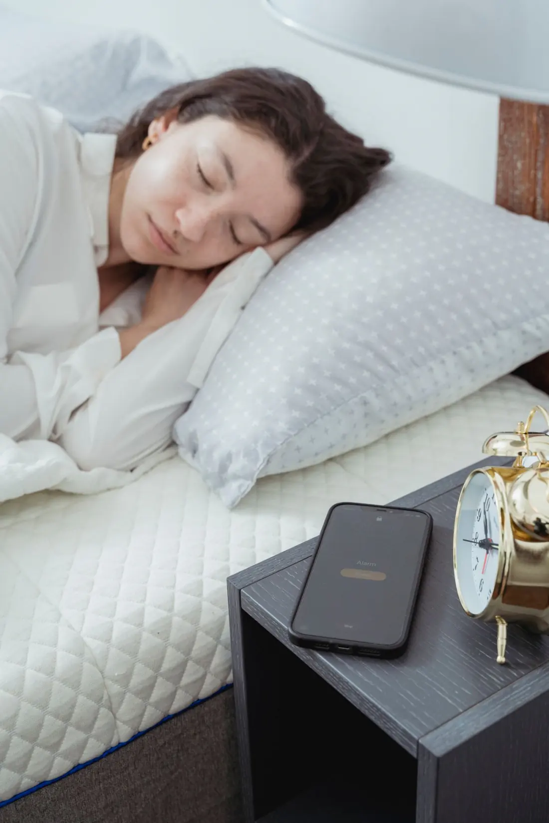 Woman still asleep as the morning alarm clock goes off on the bedside table