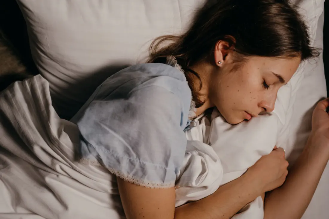 Woman sleeping peacefully in bed, the kind of unbroken night Sleep Revive is marketed for